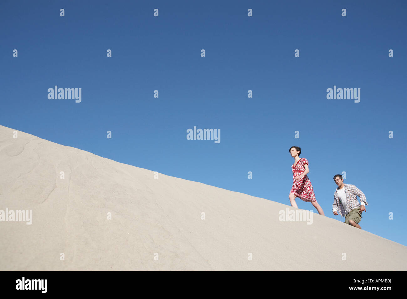 Couple ascending sand dune (low angle view) Stock Photo