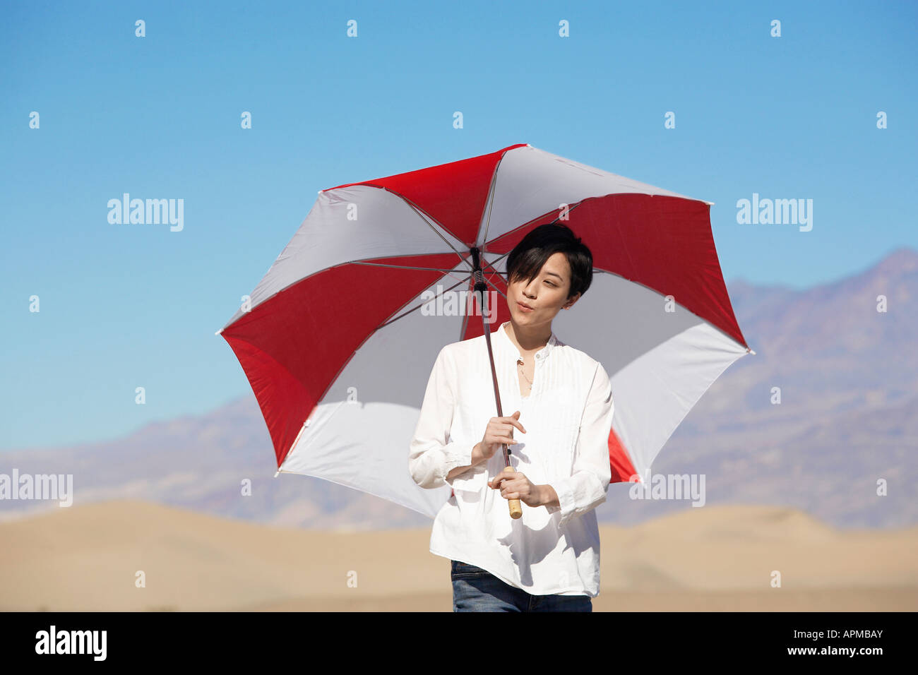 Young woman walking under umbrella in desert Stock Photo - Alamy