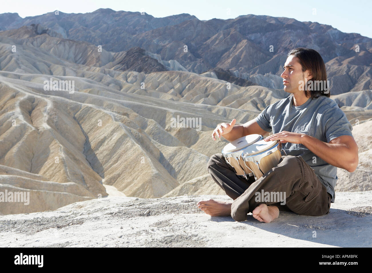 Man playing drums in desert, Death Valley, California, USA Stock Photo