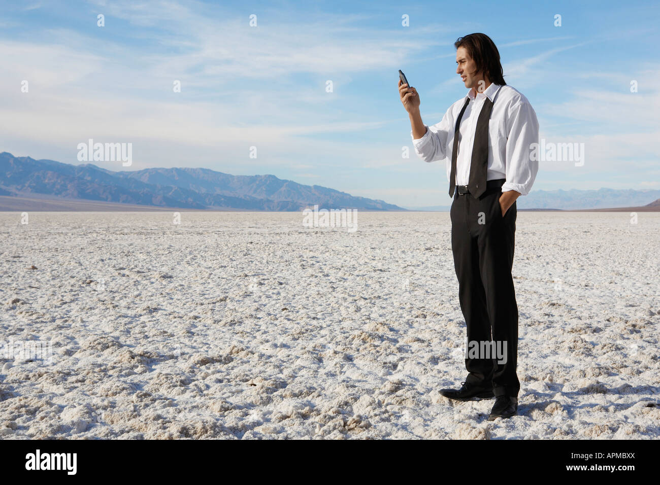Businessman using cell phone in desert Stock Photo