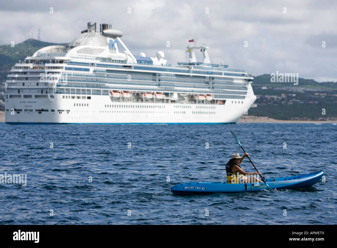 Paddler in sea kayak passes anchored cruise ship Cabo San Lucas Baja California Mexico Stock