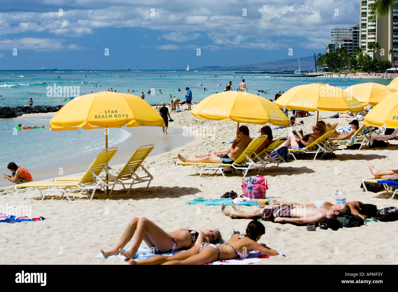 Young bikini women relax on popular beach bright yellow umbrellas