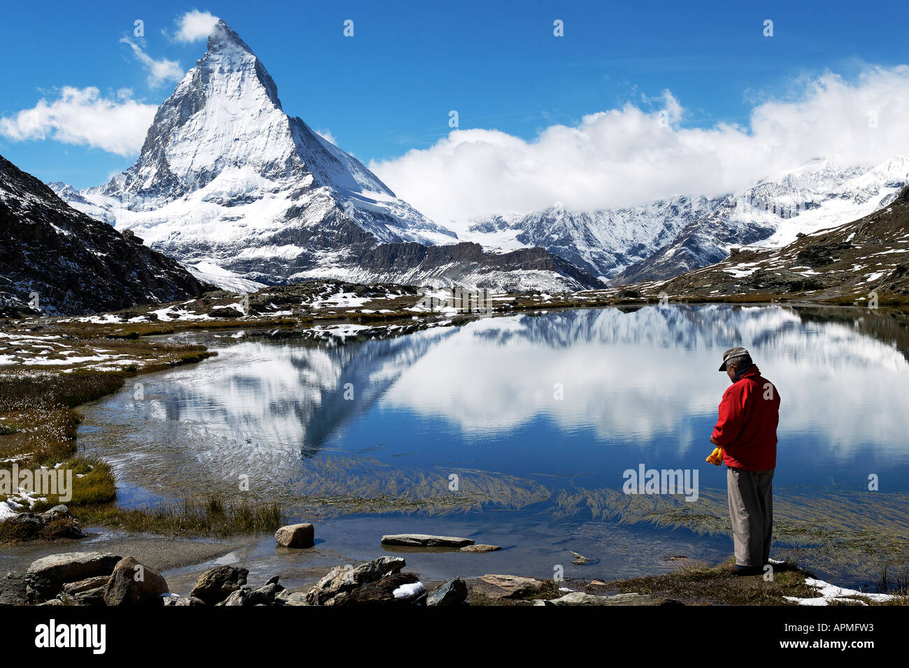 Man reflecting, and Matterhorn reflected in Riffelsee Stock Photo