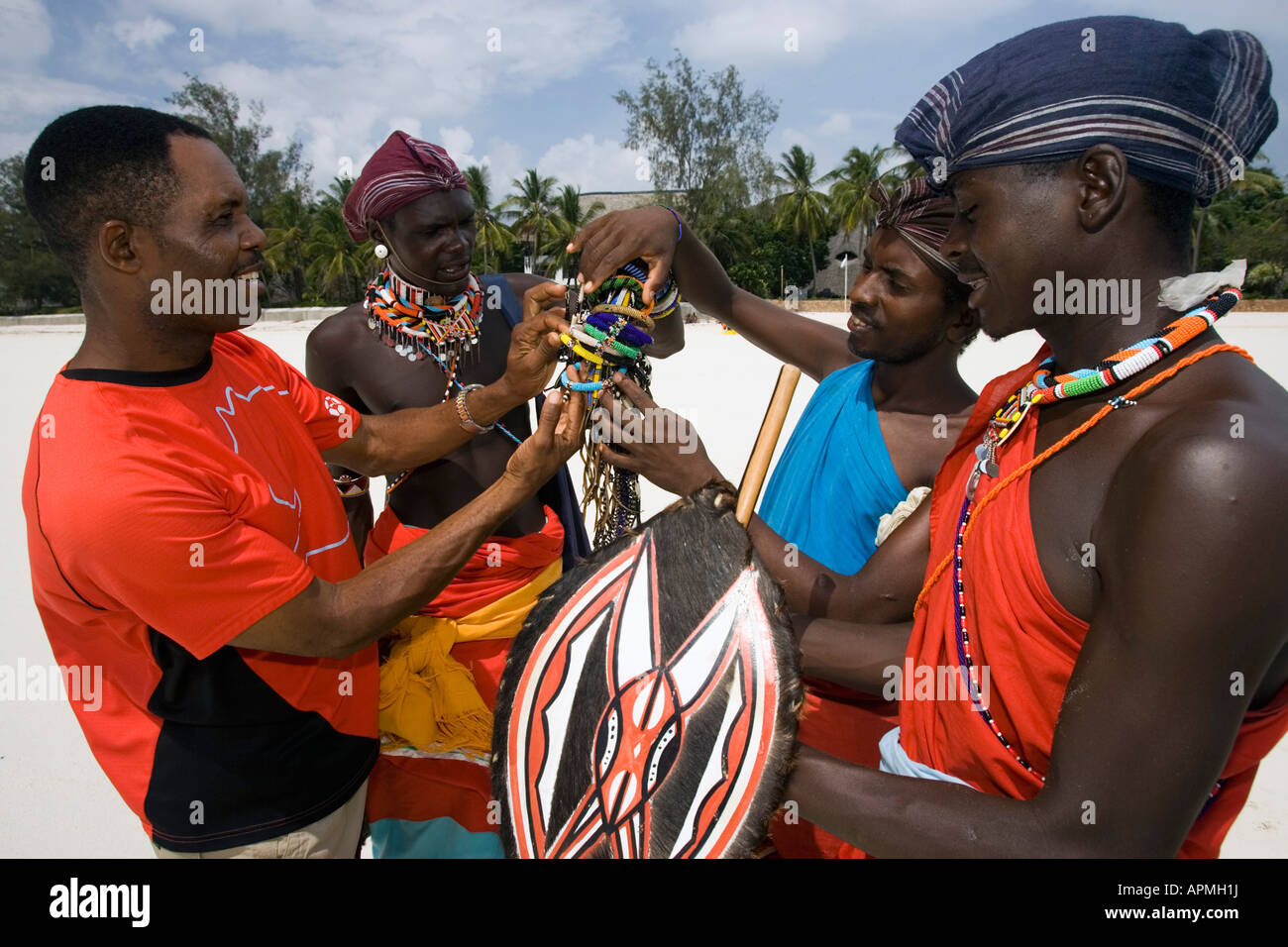 Kenyan man bargains with young Maasai tribesmen for bead handicrafts