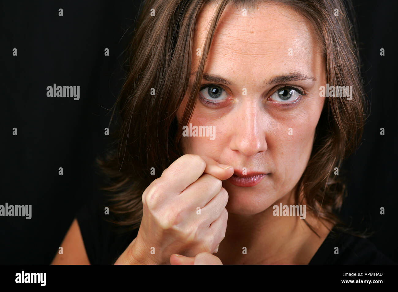 Attractive young woman holds clenched fists up to her face protective Attractive young woman holds clenched fists up to her face protective