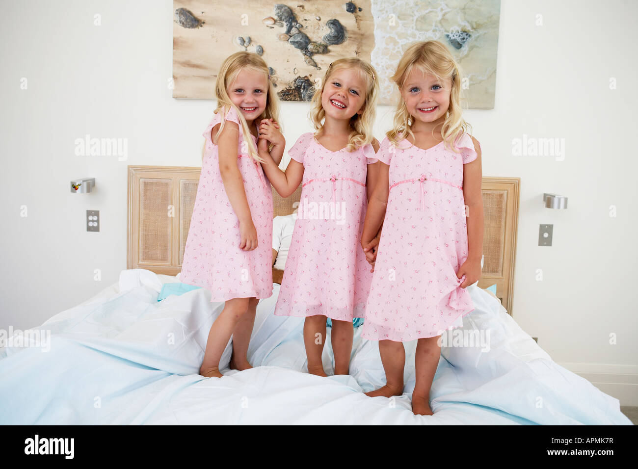 Triplets standing on bed (portrait Stock Photo Alamy