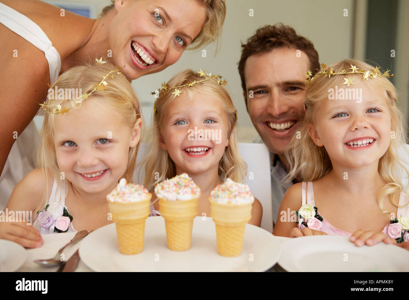 Triplets having ice cream, parents in background Stock Photo Alamy