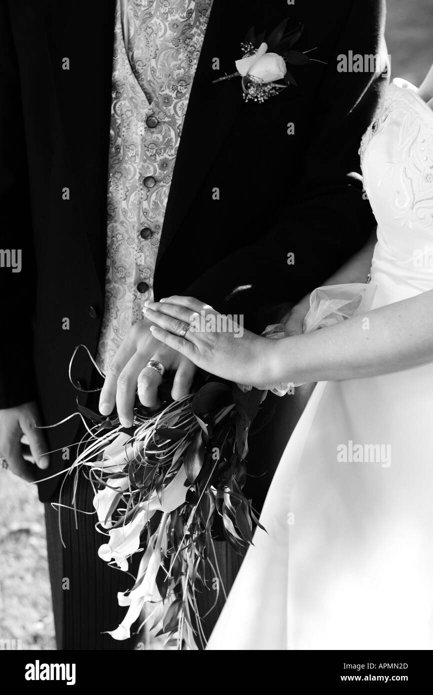 Abstract black and white Bride and Groom closeup showing wedding rings bands button hole and brides flowers and dress Stock Photo