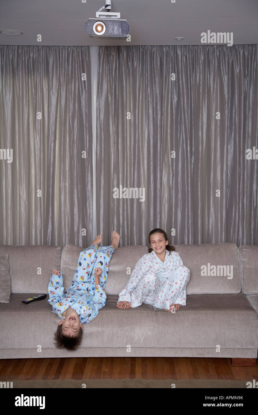 Sister and brother watching TV, boy upside down Stock Photo