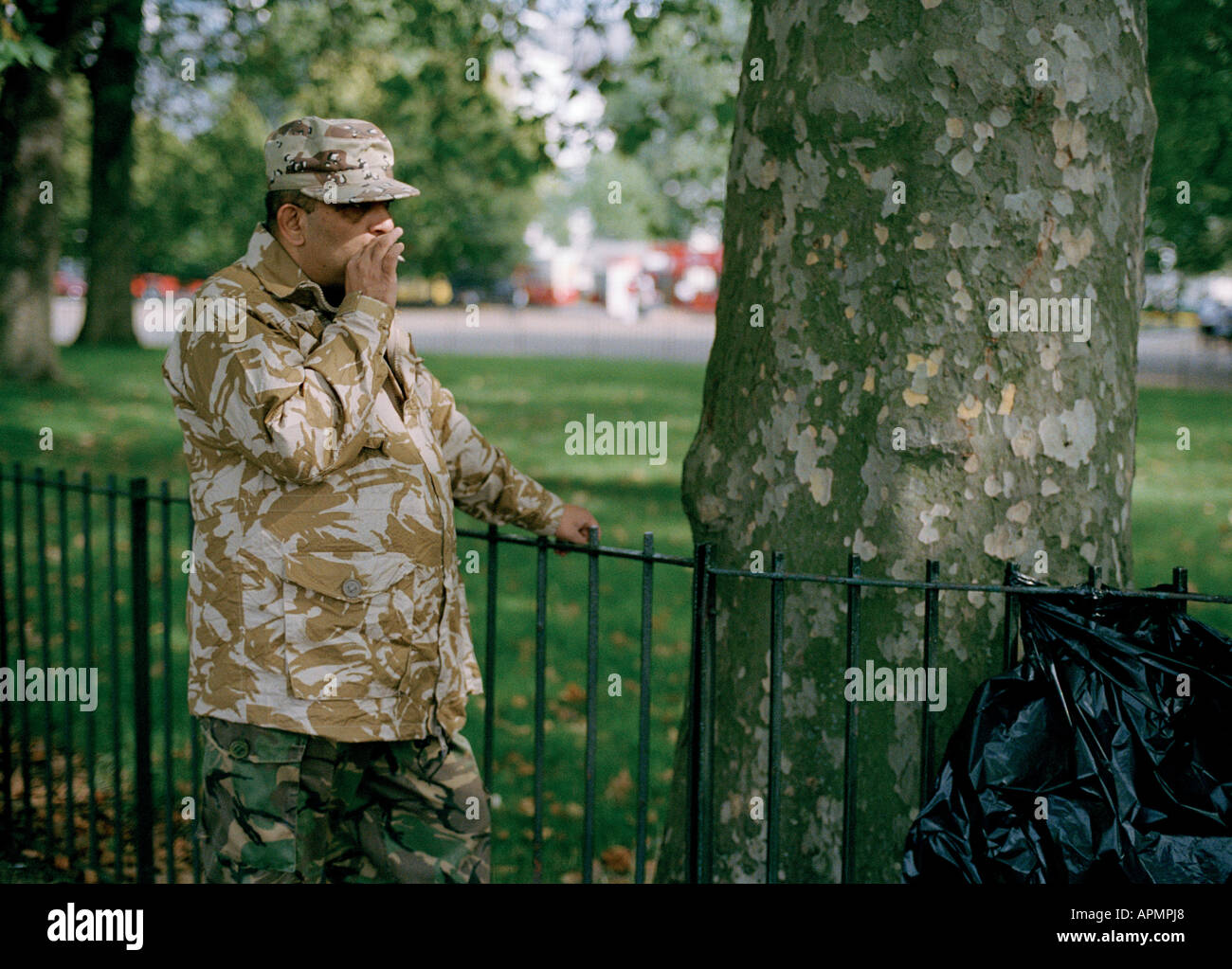 Man in camouflage clothing smoking a cigarette near Speakers' Corner in Hyde Park, London Stock Photo