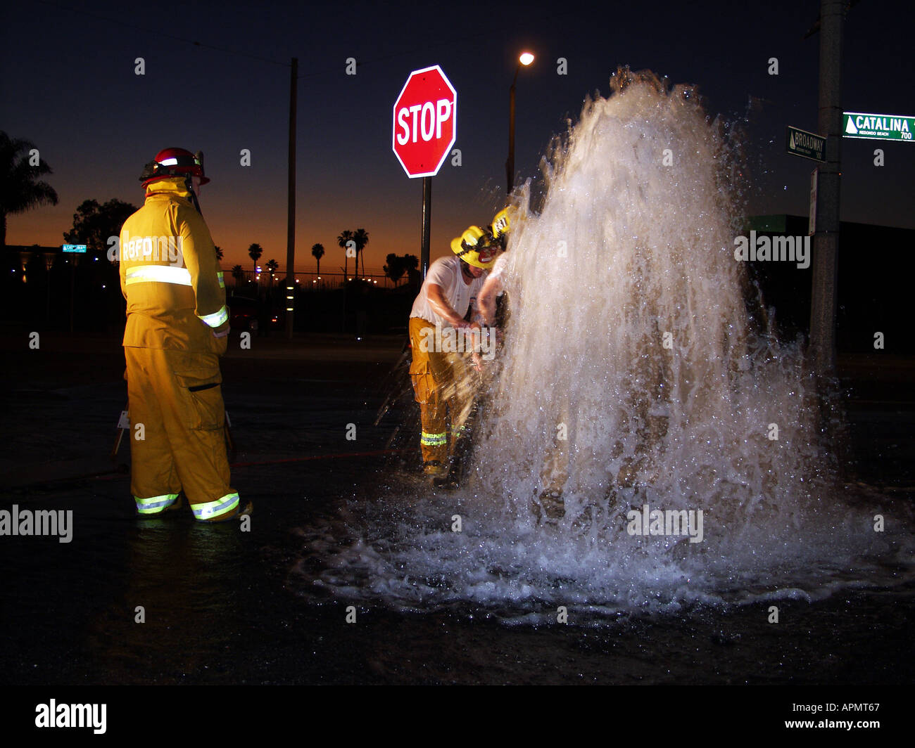 Firemen attempt to repair fire hydrant at night that was knocked over by errant driver. Redondo Beach, CA.USA Stock Photo