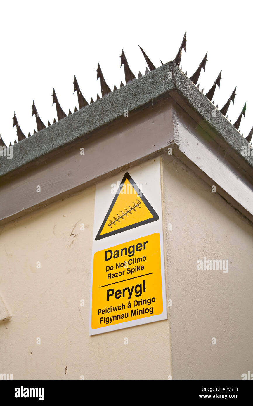 Security razor spikes along edge of roof with bilingual warning sign Bersham Wrexham Wales UK Stock Photo