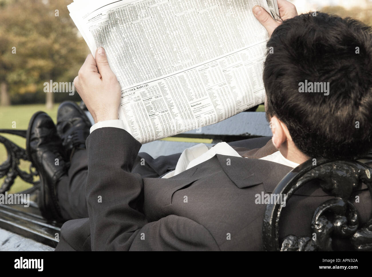 Man reading the newspaper on park bench Stock Photo - Alamy