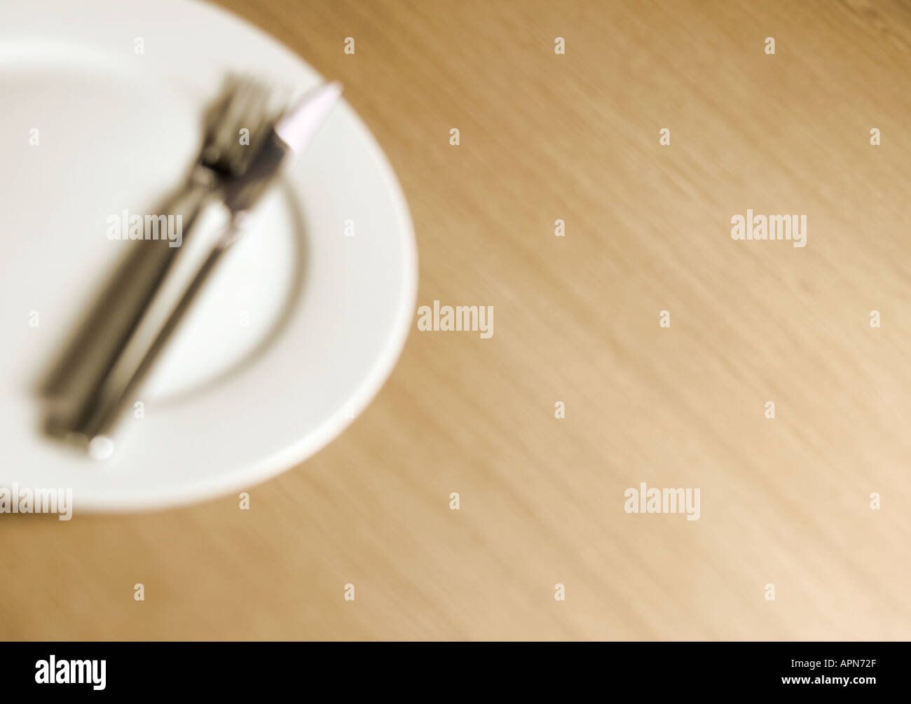 Empty clean dinner plate with knife and fork on tabletop Stock Photo