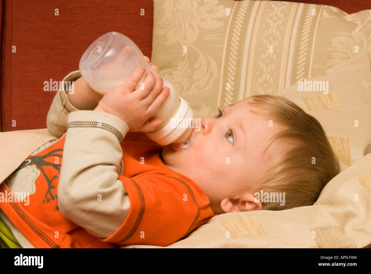 baby boy bottle feeding himself milk ten months old Stock Photo Alamy