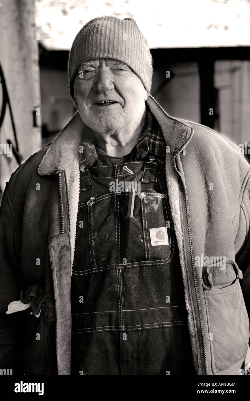 senior male blacksmithing in outdoor farm shop Stock Photo