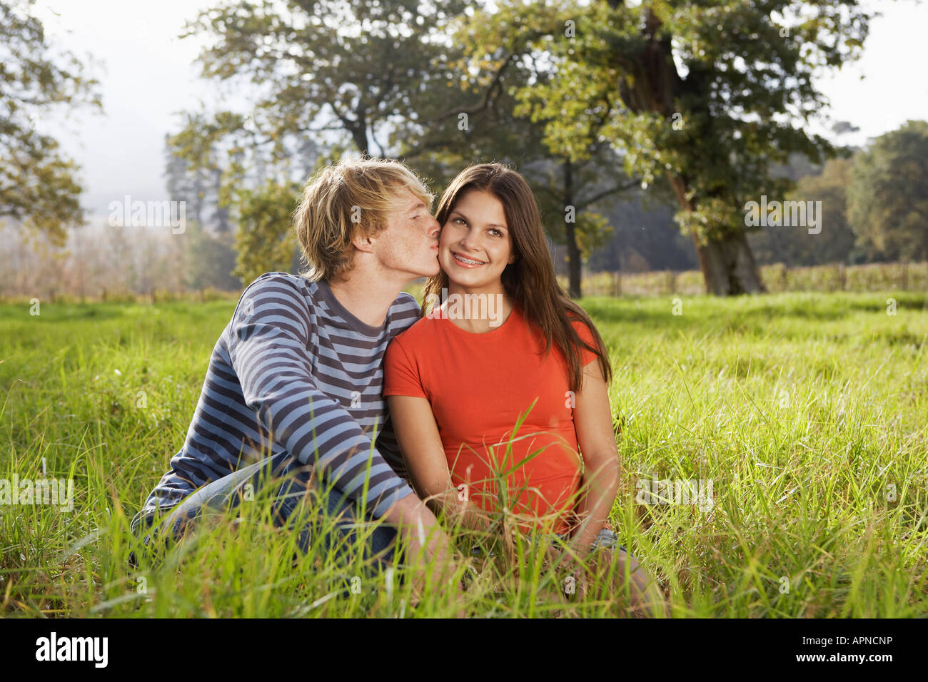 Teenage couple sitting in field Stock Photo