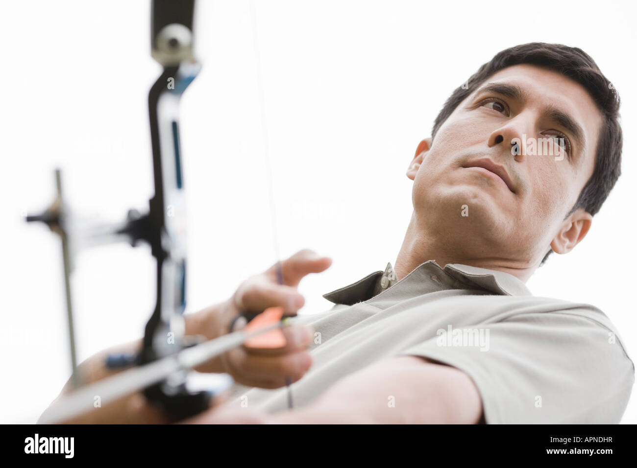 Mid adult man with bow and arrow (low angle view) Stock Photo