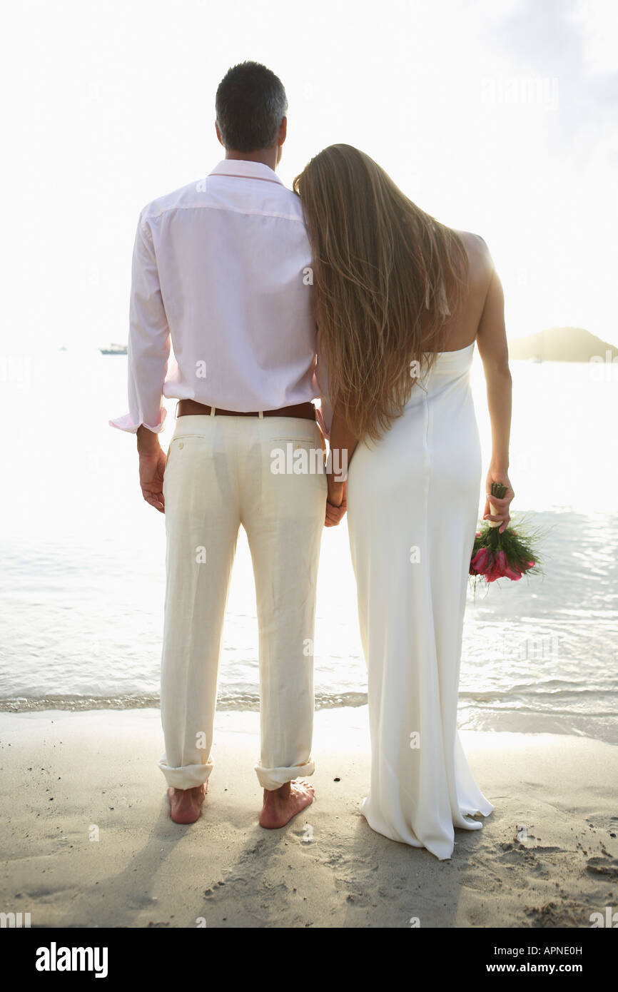 Newlyweds looking at view on beach (rear view) Stock Photo
