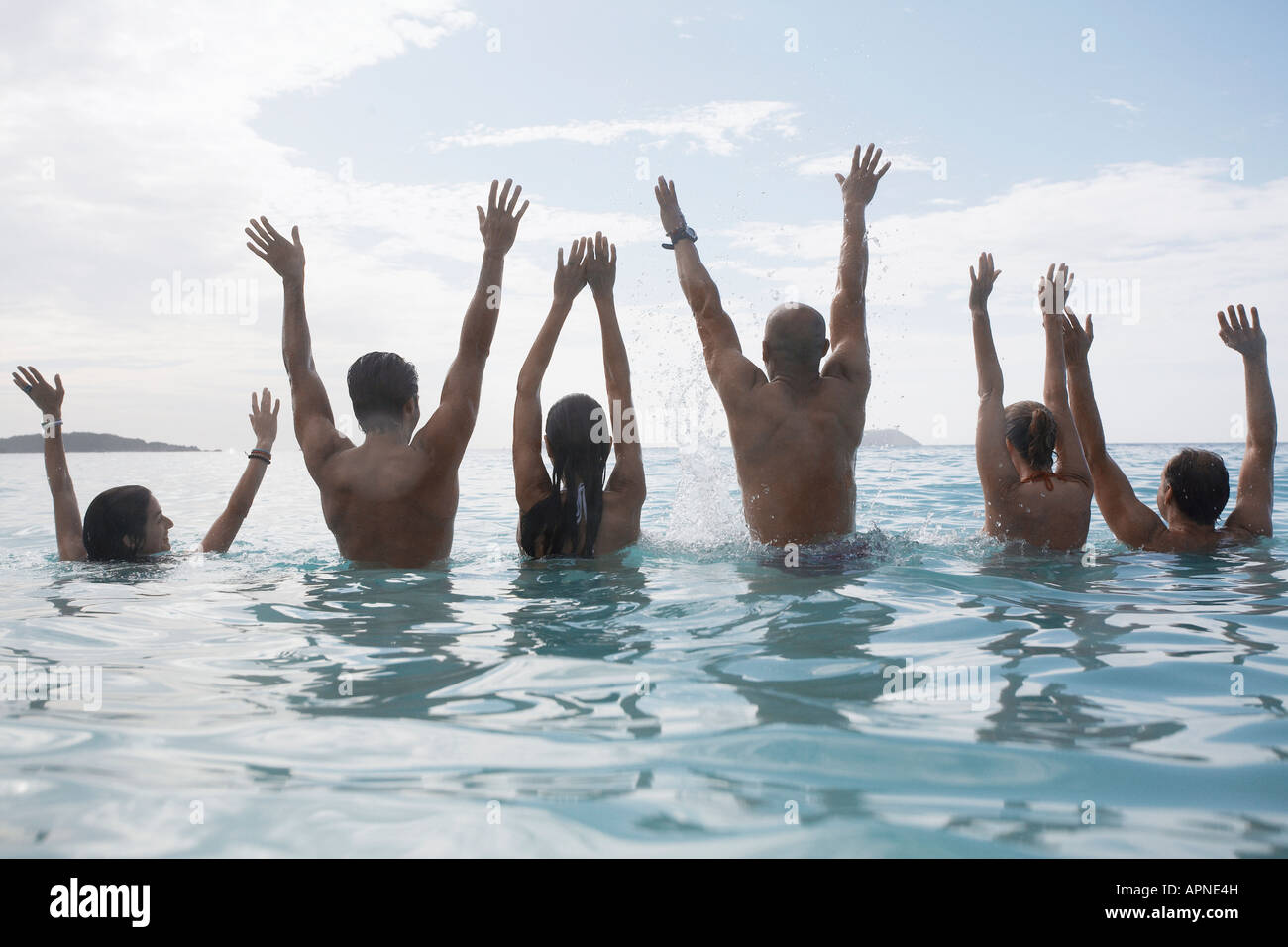 Six people raising hands in sea, St. John, US Virgin Islands, USA Stock Photo
