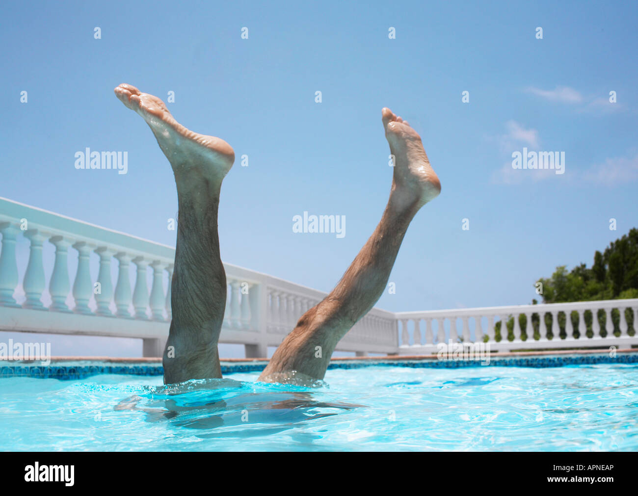 Man doing handstand in swimming pool, legs above surface Stock Photo