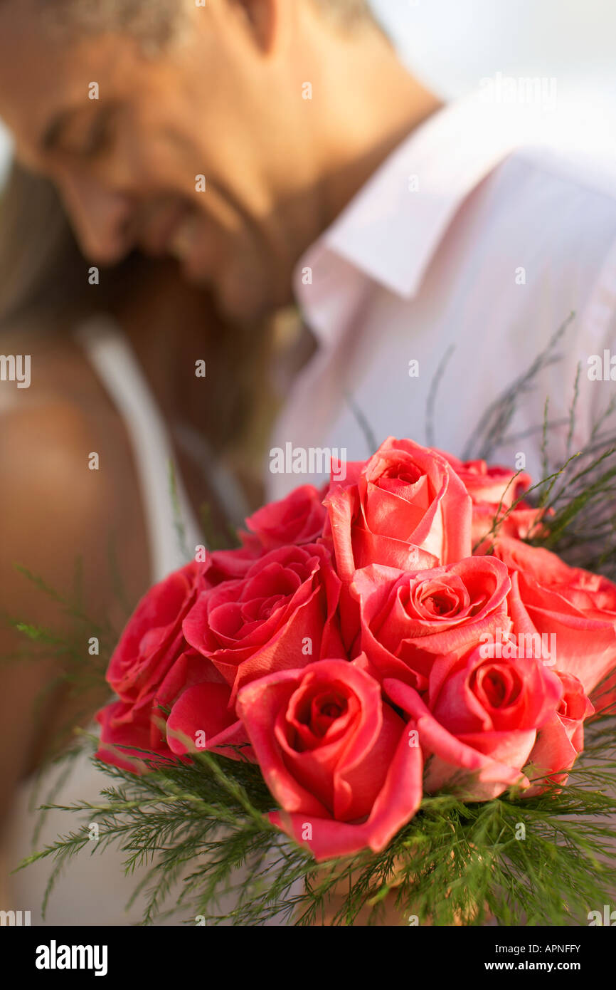 Newlyweds hugging (focus on flowers) Stock Photo