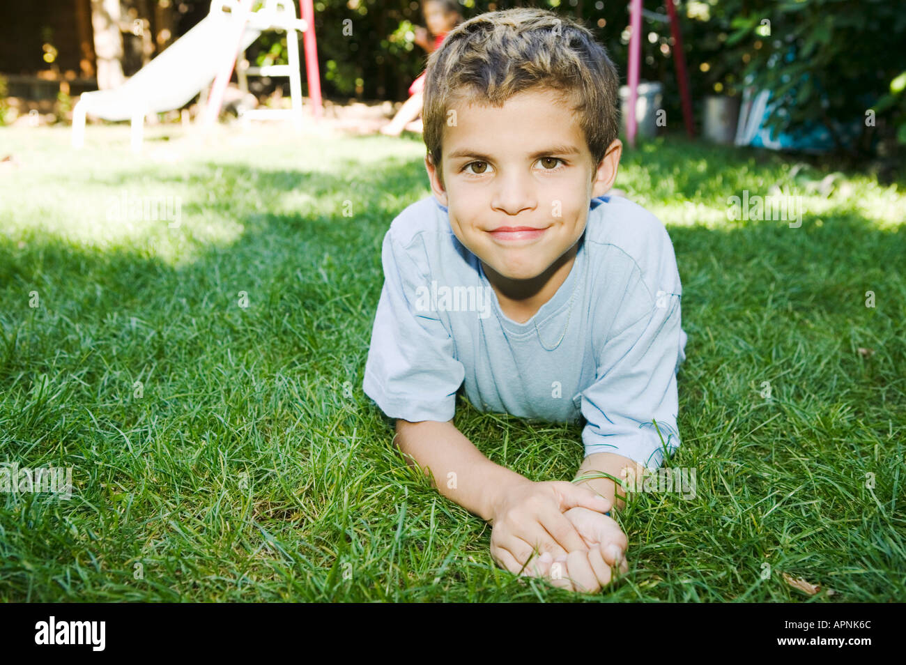Smiling boy laying on grass lawn Stock Photo