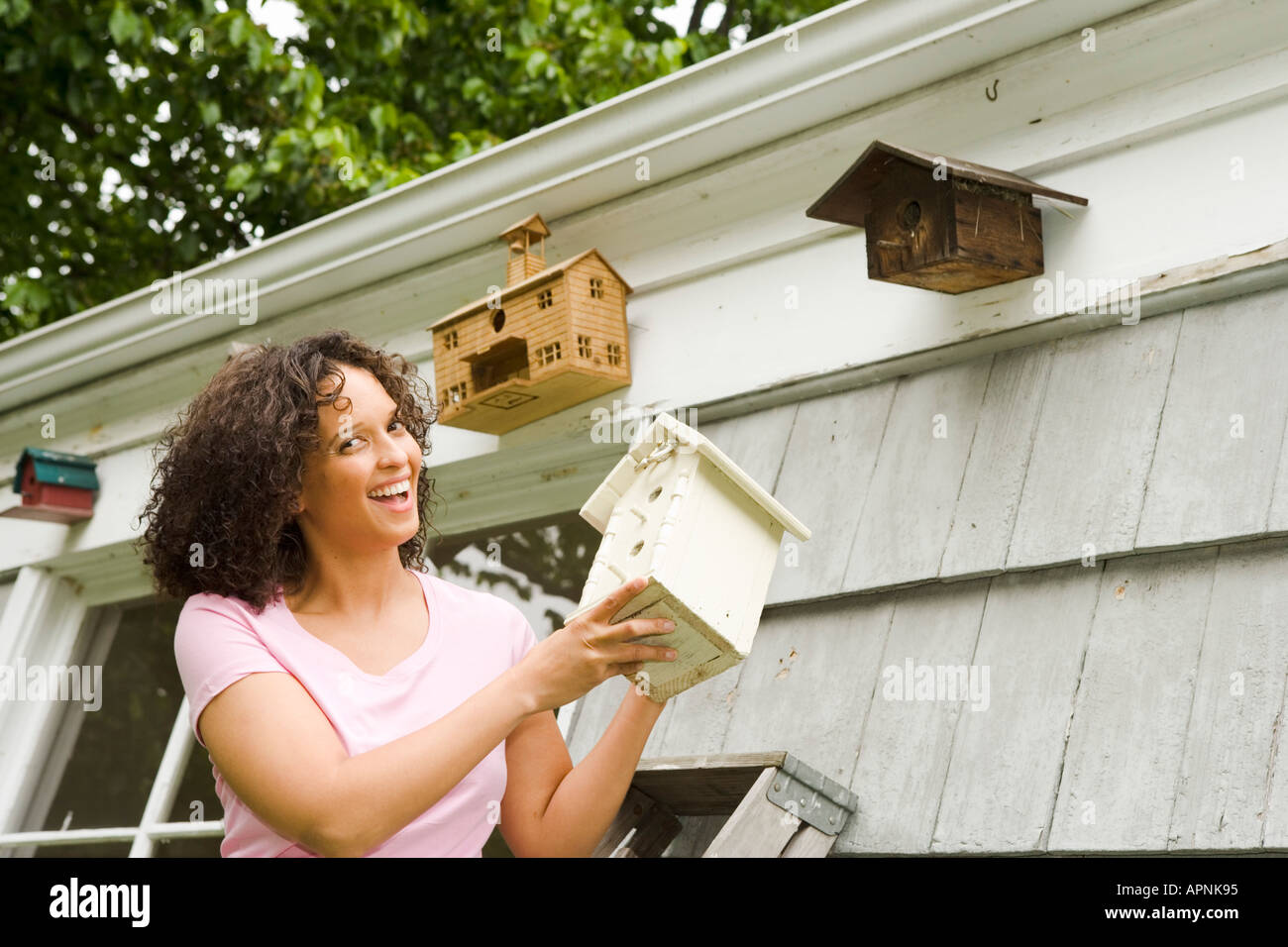 Smiling woman adding to birdhouse collection Stock Photo