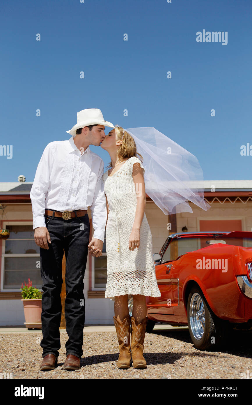 Newlyweds in cowboy attire kissing Stock Photo