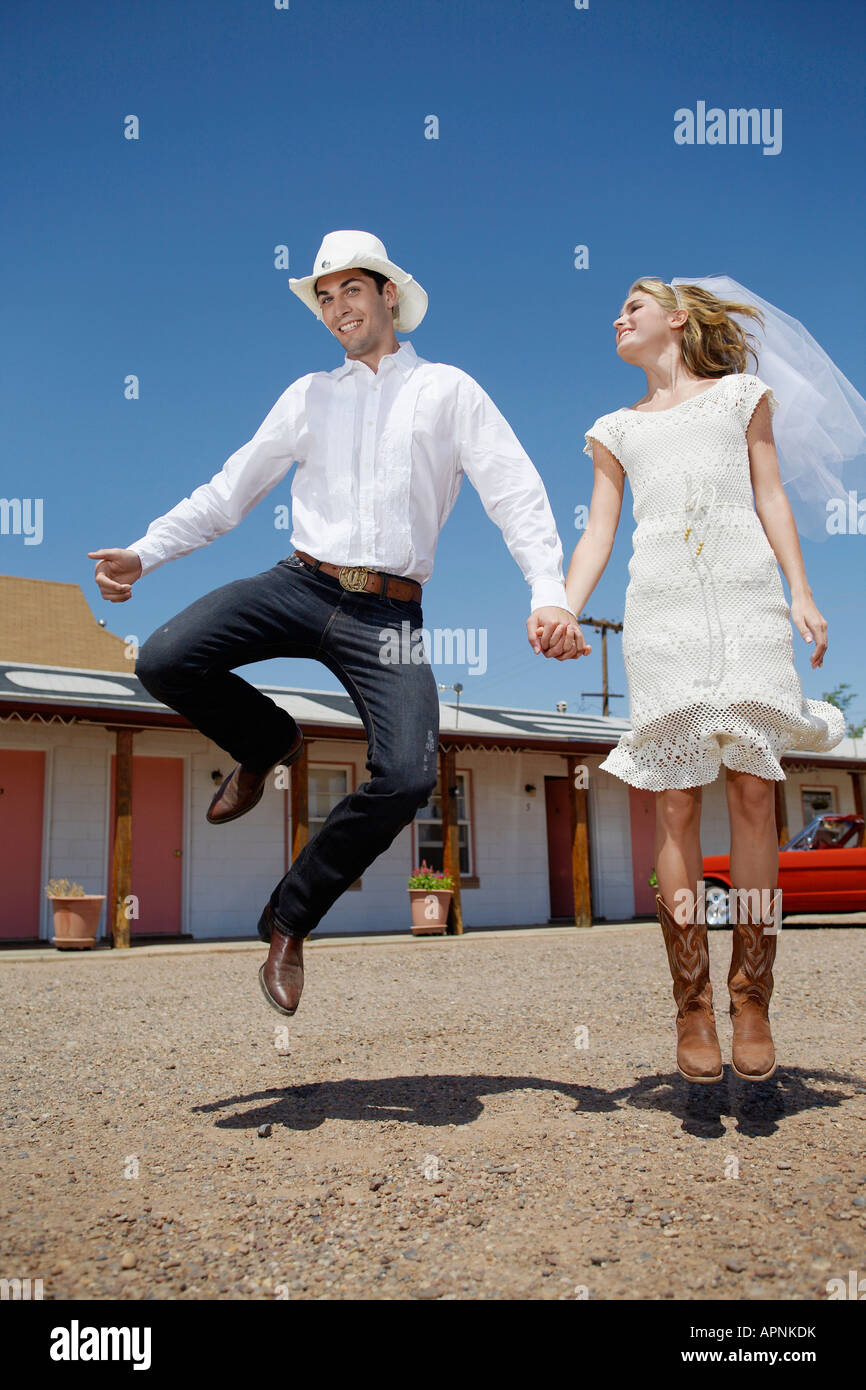 Newlyweds in cowboy attire jumping of joy Stock Photo