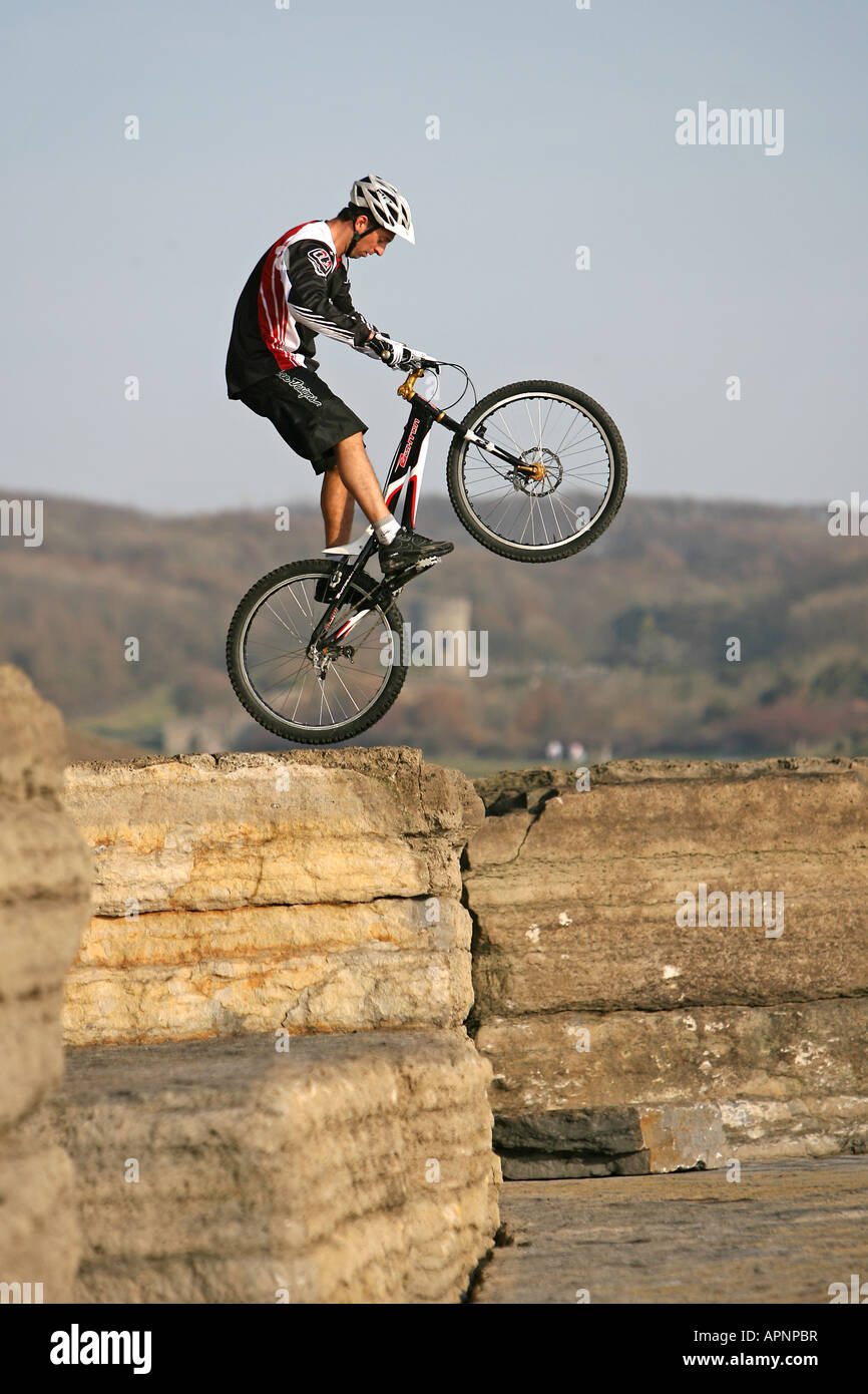 A Mountain Biker perfoms a stunt on some rocks. Stock Photo