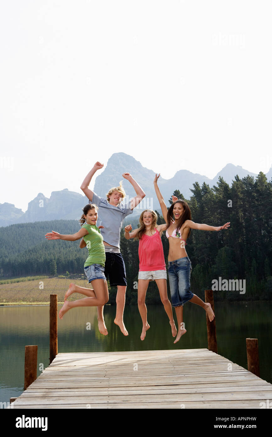 Four Teenagers Jumping on Jetty Stock Photo