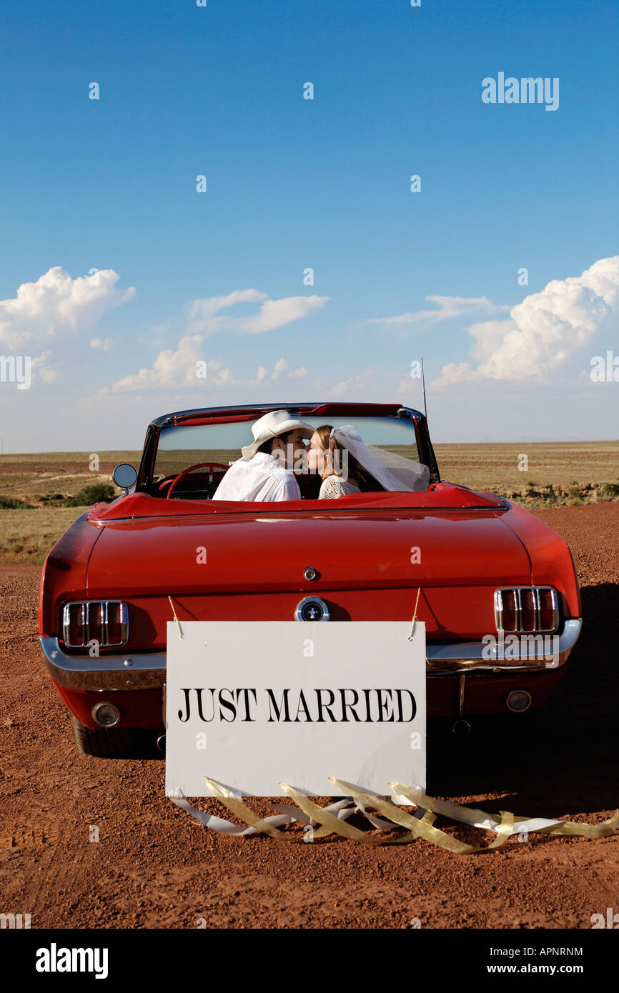 Newlyweds kissing in convertible Stock Photo