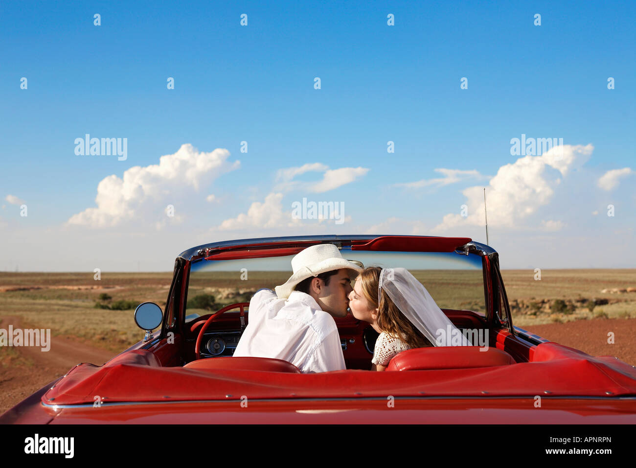 Newlyweds kissing in convertible Stock Photo