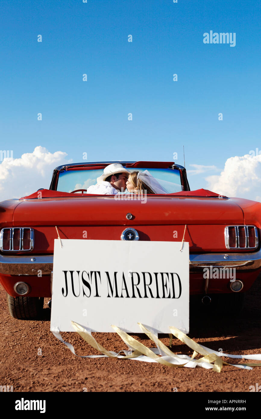 Newlyweds kissing in convertible Stock Photo