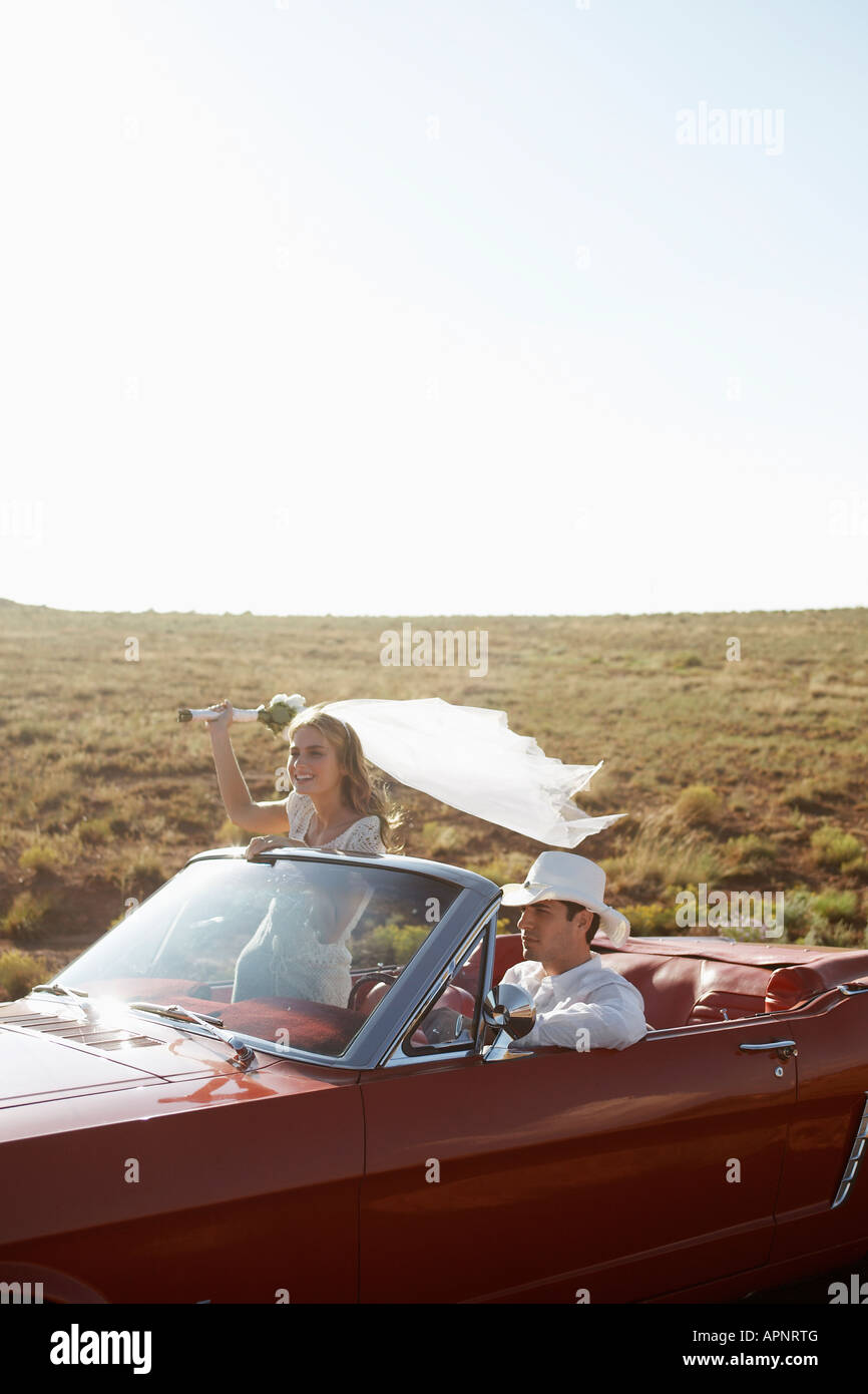 Newlyweds driving convertible through desert, Arizona, USA Stock Photo