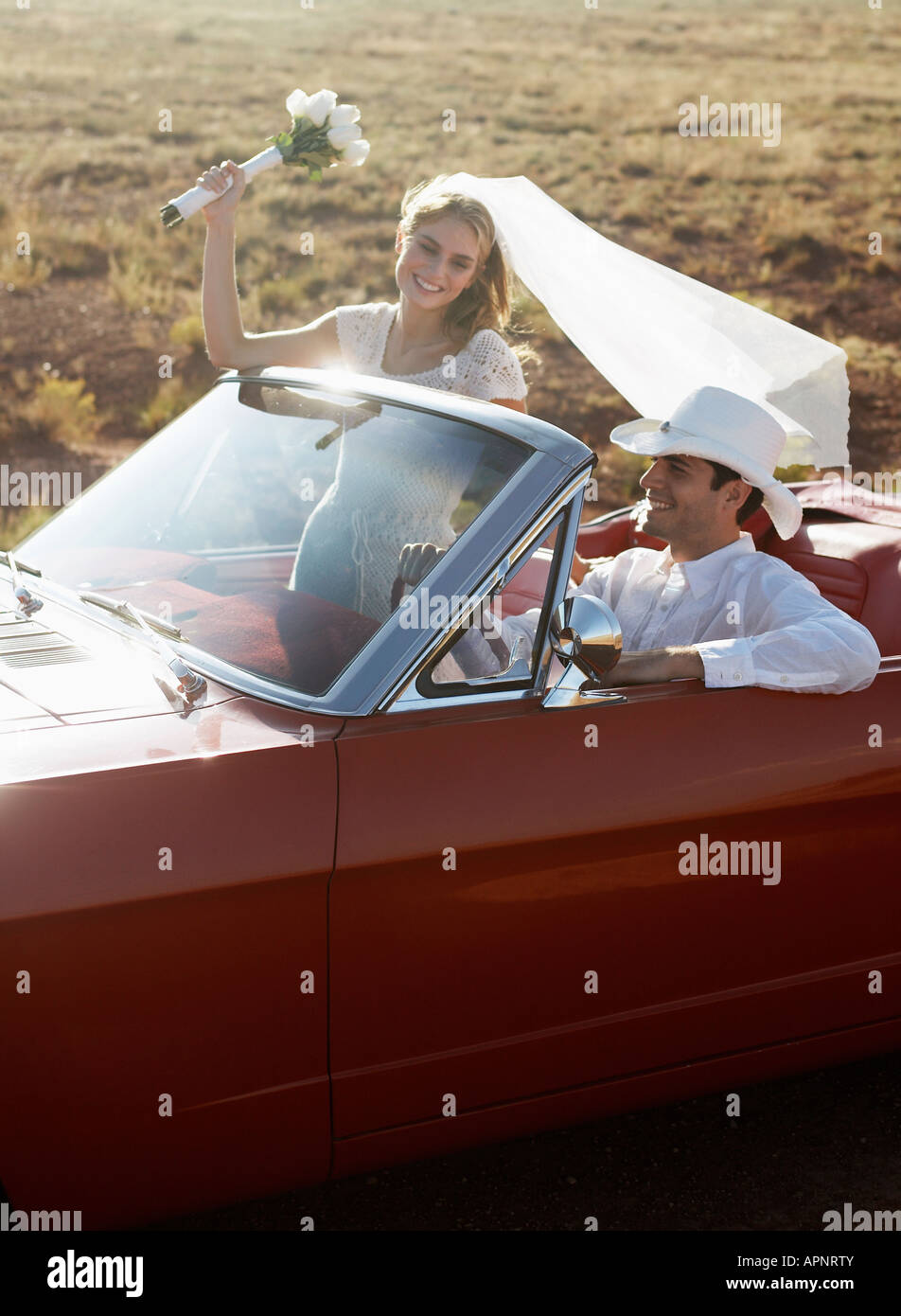 Newlyweds driving convertible through desert, Arizona, USA Stock Photo