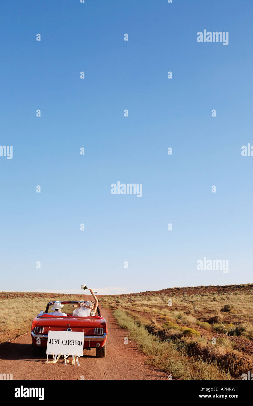 Newlyweds driving convertible through desert, Arizona, USA Stock Photo