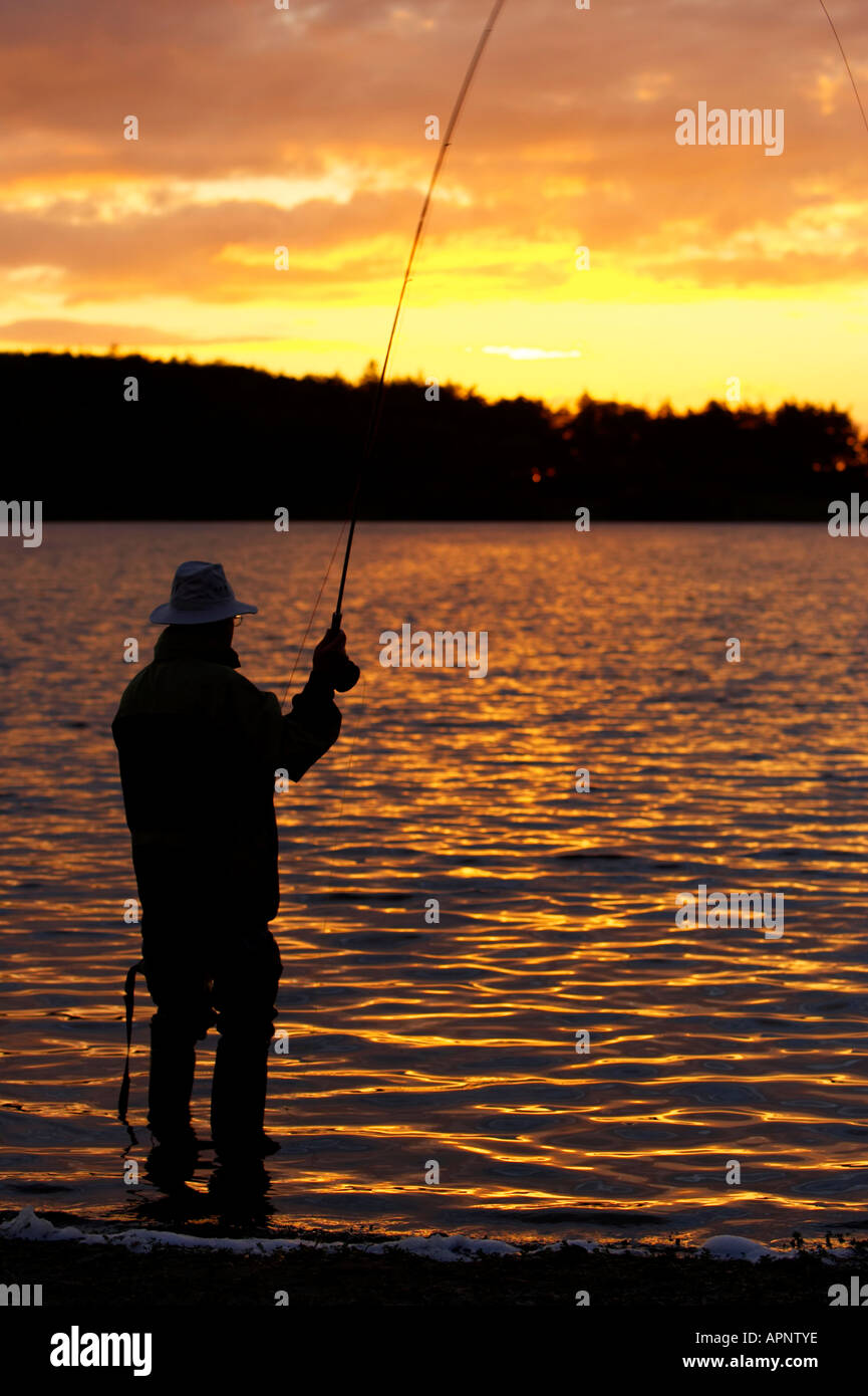 fisherman fly fishing casting on Stoneyford Reservoir at sunset county antrim northern ireland Stock Photo