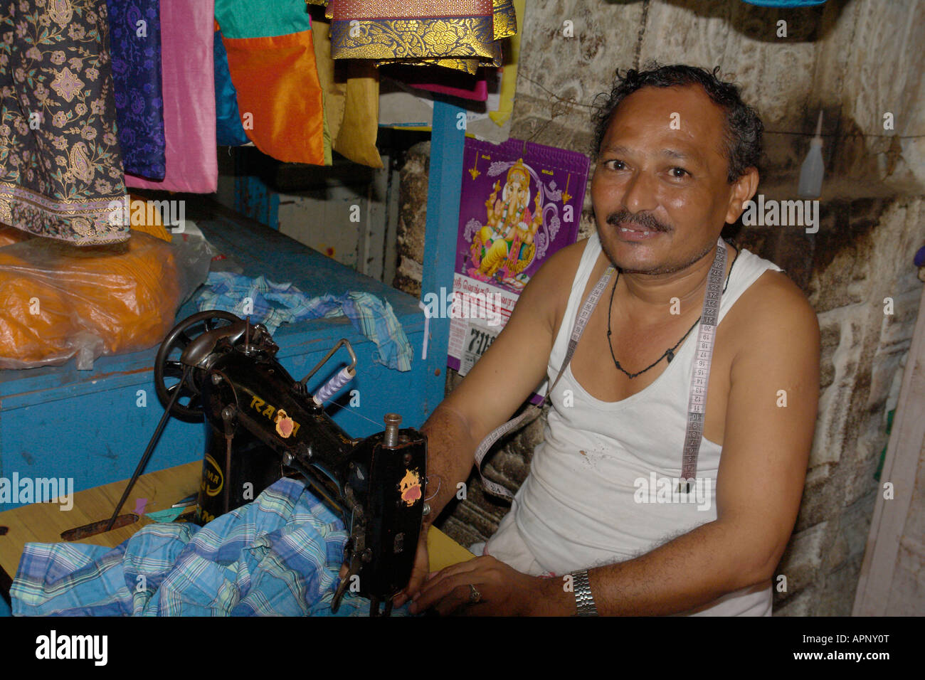 indian tailor with traditional sewing machine in madurai market Stock