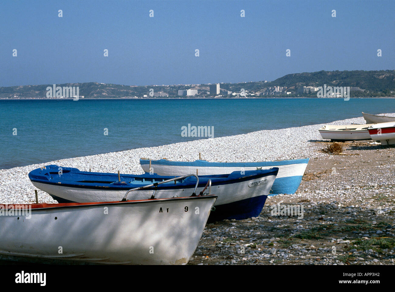 Painted blue and white boats pulled up the pebbled beach in the resort of Ixia on the outskirts of Rhodes town Stock Photo
