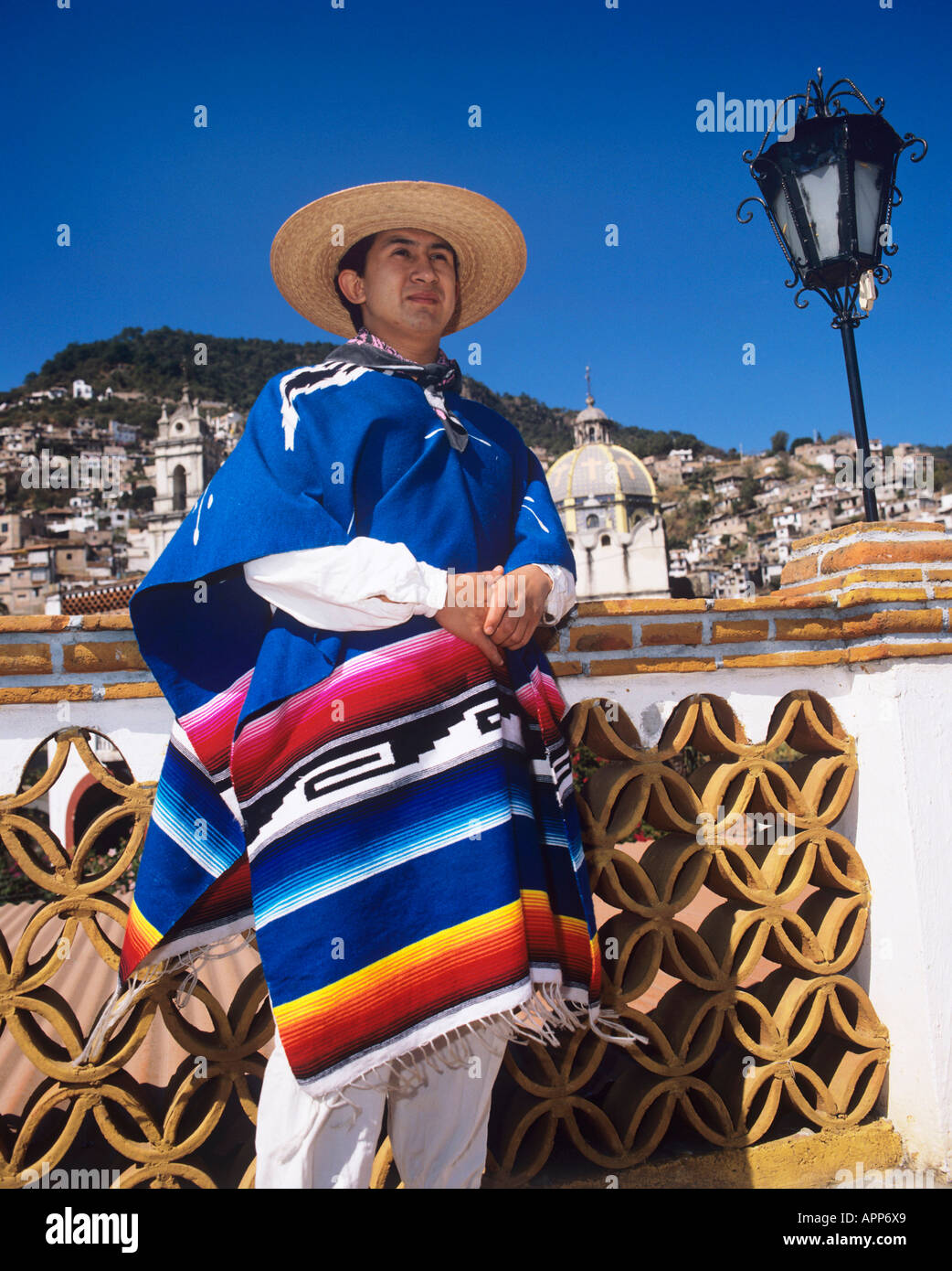 Local Mexican in traditional sombrero and poncho standing next to a  decorative wall with city building behind Stock Photo - Alamy