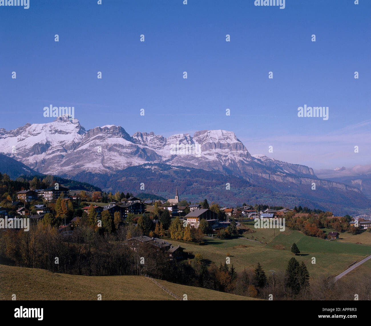 The snow covered peaks of Chaine des Aravis looming over the hillside village of Combloux Stock Photo