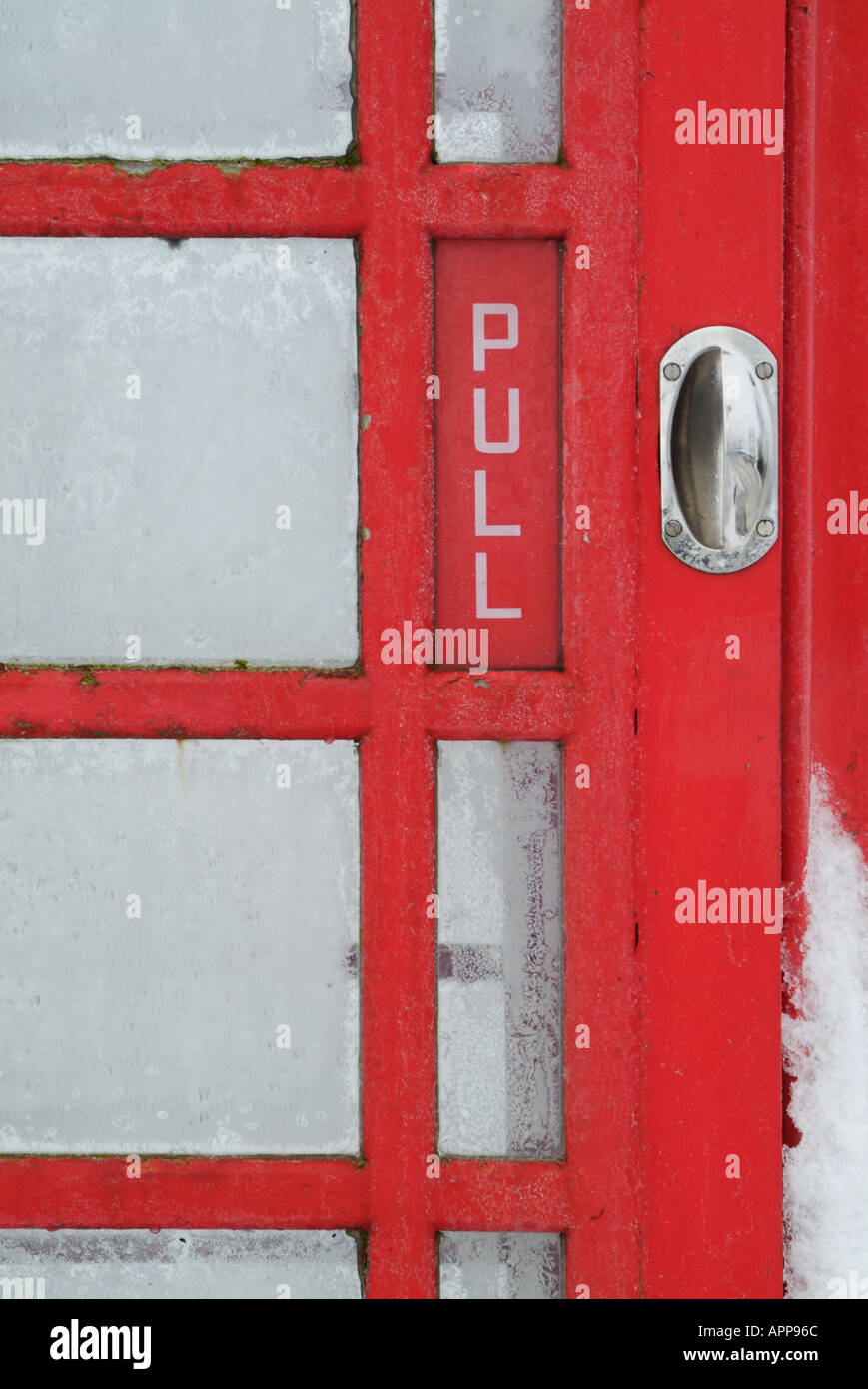Snow covered door and glass panes of traditional red telephone box in derbyshire peak district England UK GB EU Europe Stock Photo