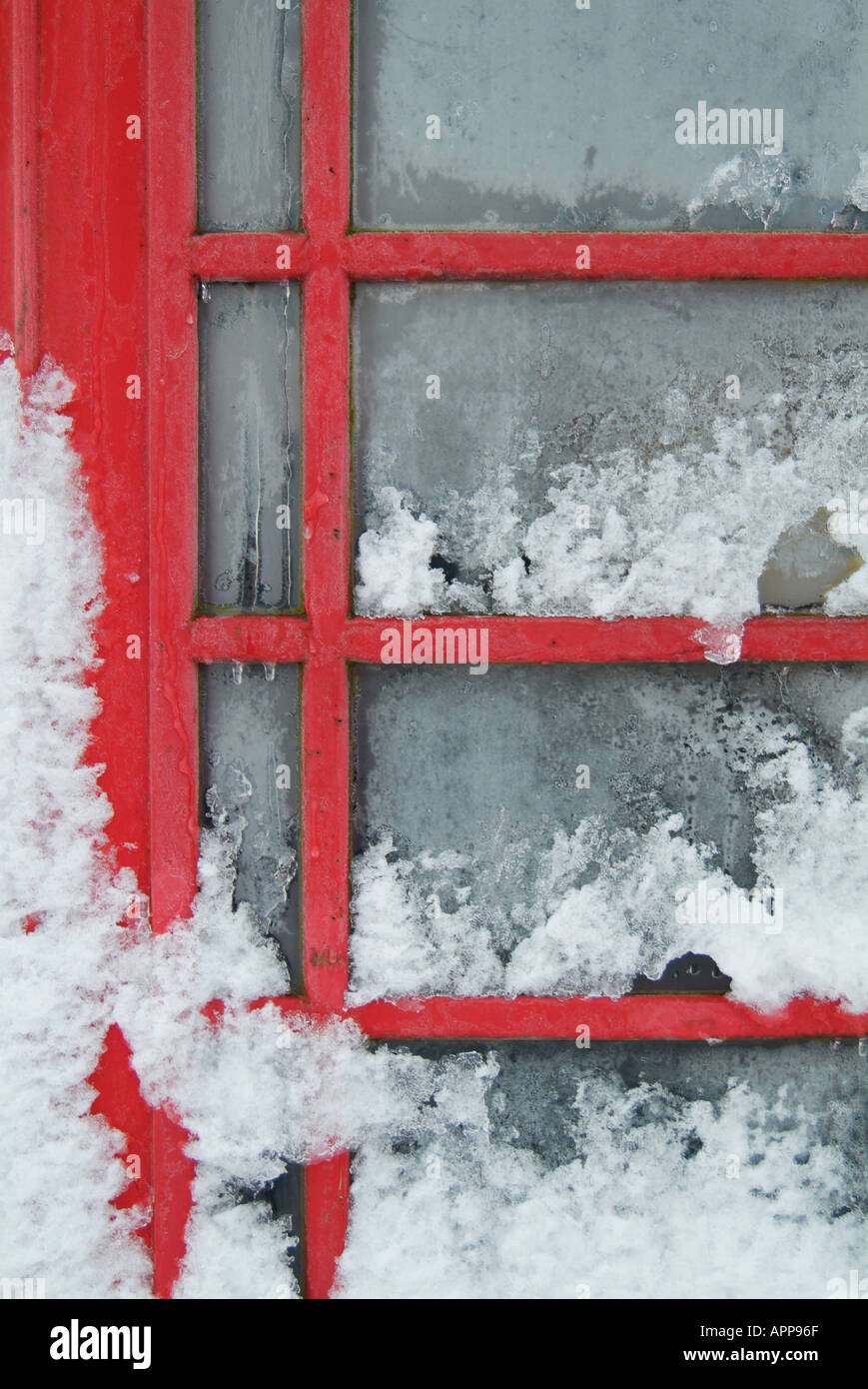 Snow covered door and glass panes of traditional red telephone box in derbyshire peak district England UK GB EU Europe Stock Photo