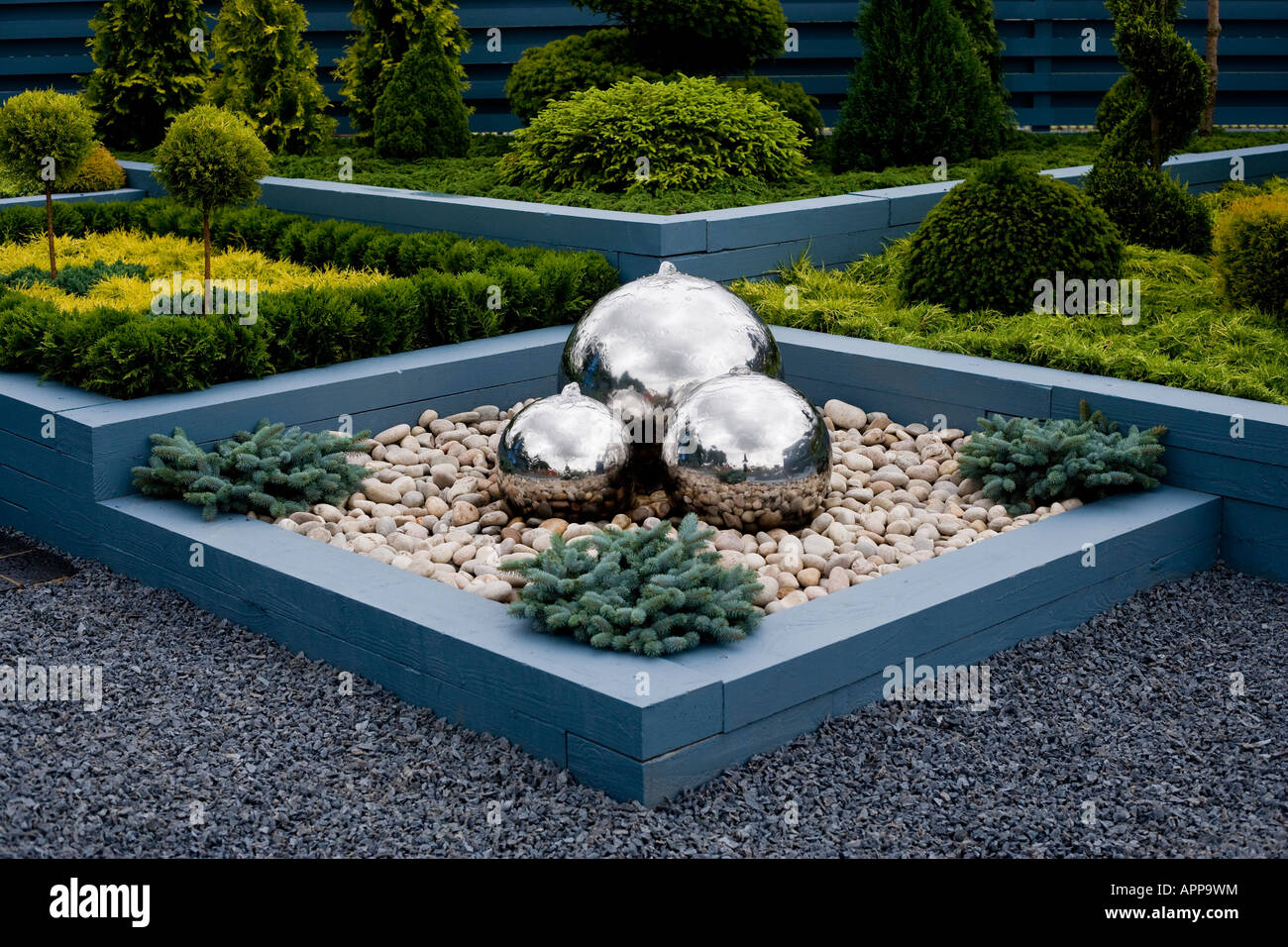 Stainless steel water feature with dwarf Picea (pine) and other conifers Stock Photo