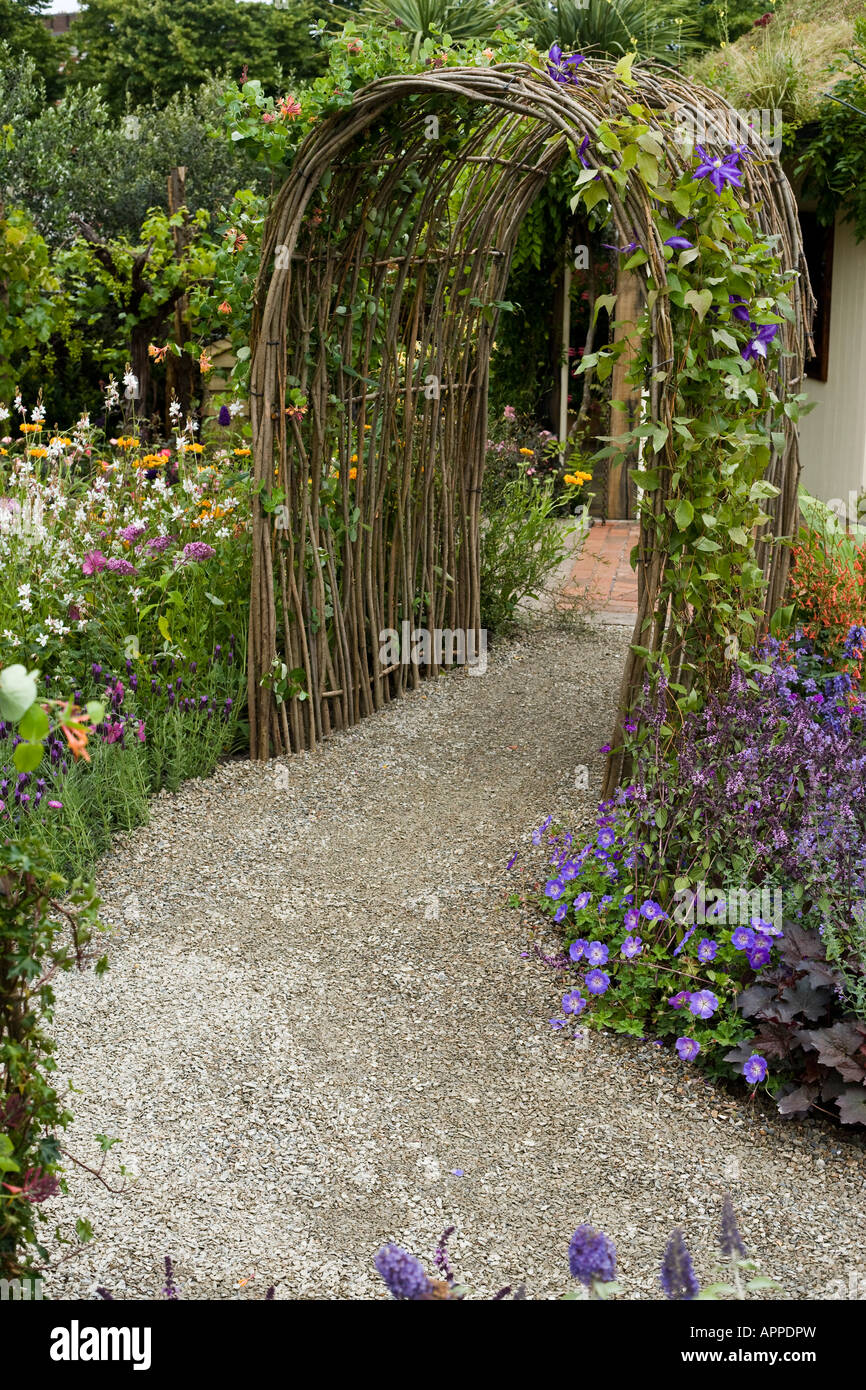 Willow archway with clematis over gravel pathway Stock Photo