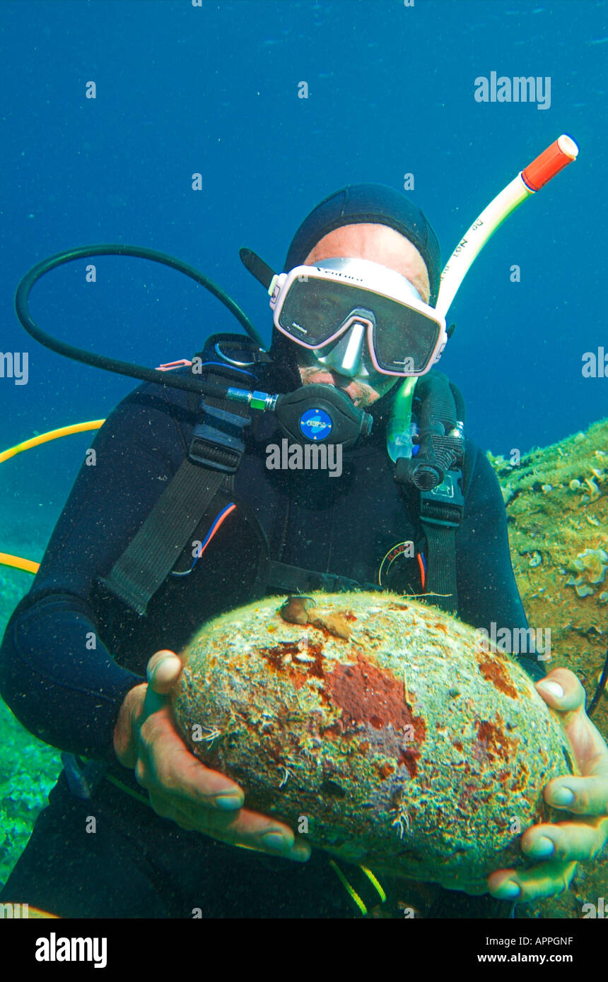 Diver holding ballast stone from ancient shipwreck at Paros Island
