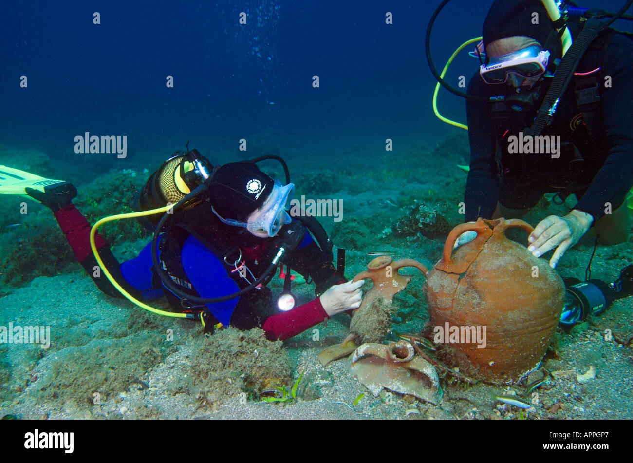 Divers holding and examining amphora from ancient shipwreck at Paros Island Greece Stock Photo