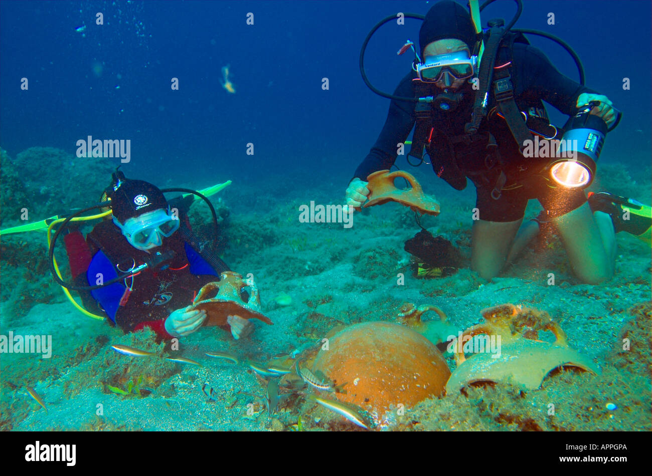 Divers holding and examining amphora from ancient shipwreck at Paros